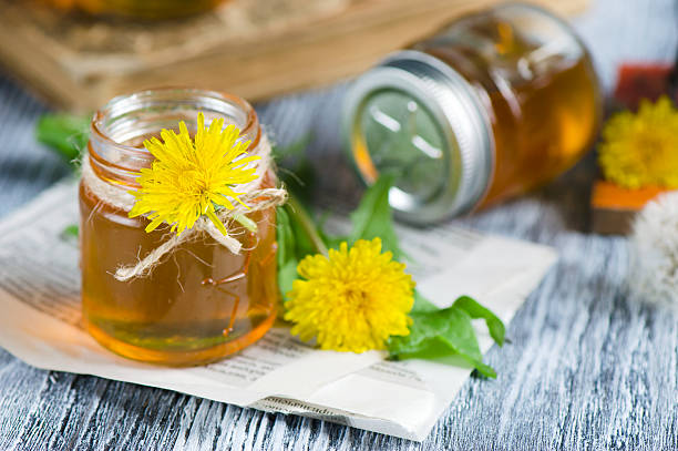 Jar with syrup of dandelion's flowers on table